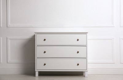Stylish chest of drawers near white wall indoors