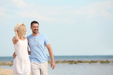 Happy romantic couple walking on beach, space for text