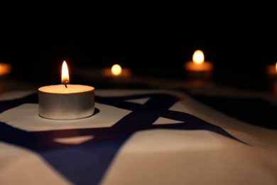 Photo of Burning candle on flag of Israel. Holocaust memory day