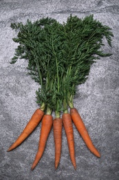 Photo of Bunch of tasty raw carrots on grey table, flat lay