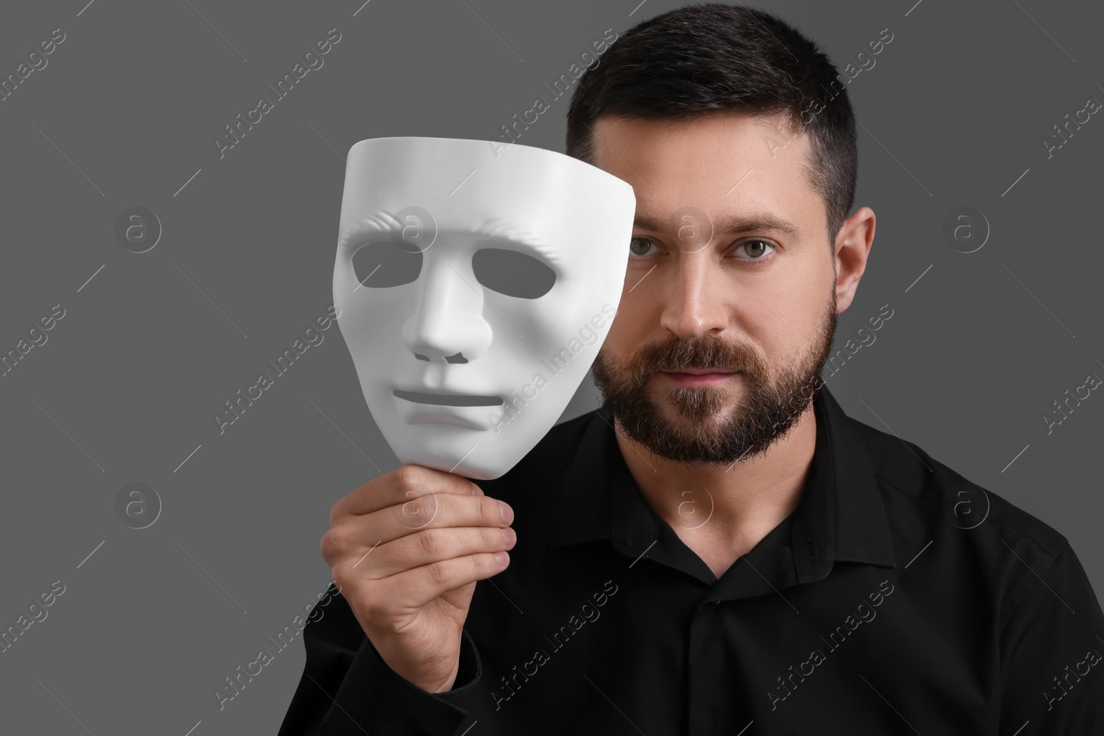 Photo of Multiple personality concept. Man with mask on grey background