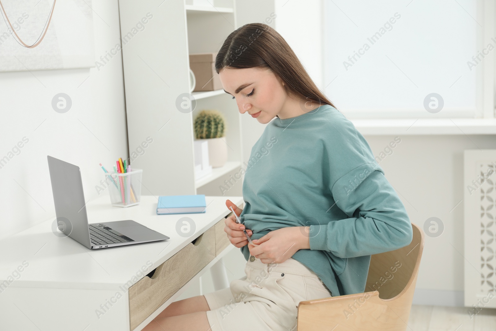 Photo of Diabetes. Woman making insulin injection into her belly at table indoors