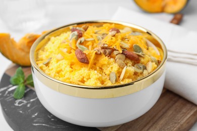 Photo of Tasty cornmeal with nuts, pumpkin and seeds in bowl on table, closeup