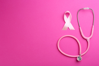 Photo of Pink ribbon as breast cancer awareness symbol and stethoscope on color background, flat lay. Space for text