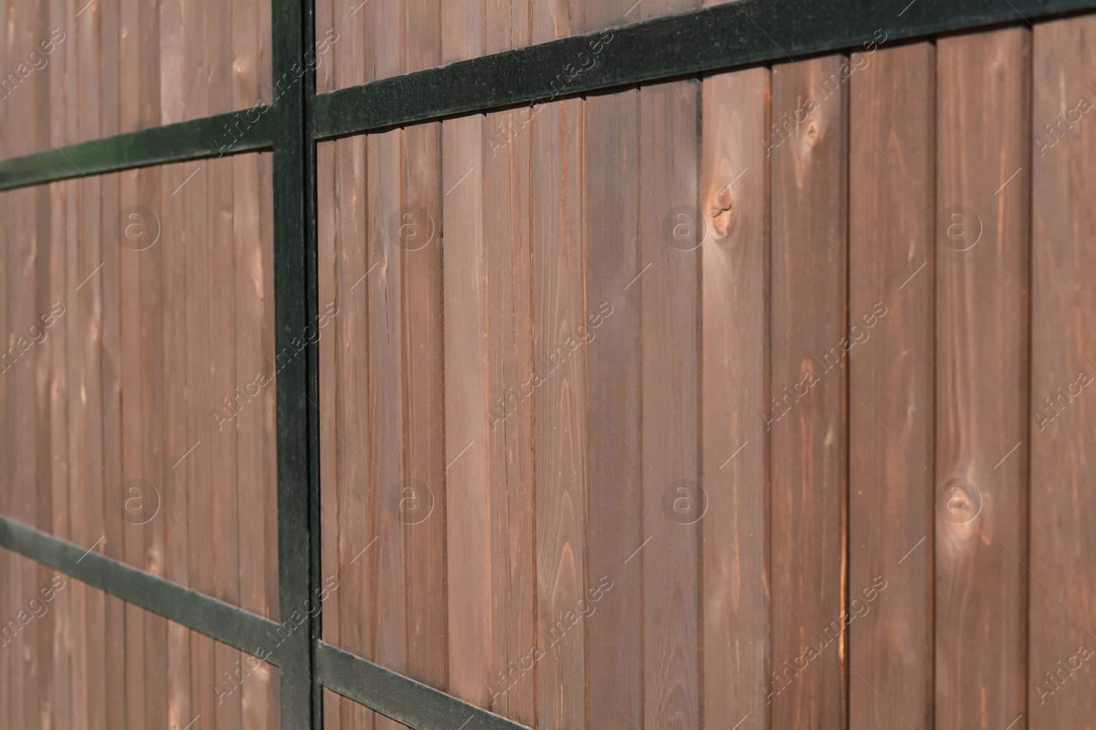 Photo of Metal and wooden fence outdoors, closeup view