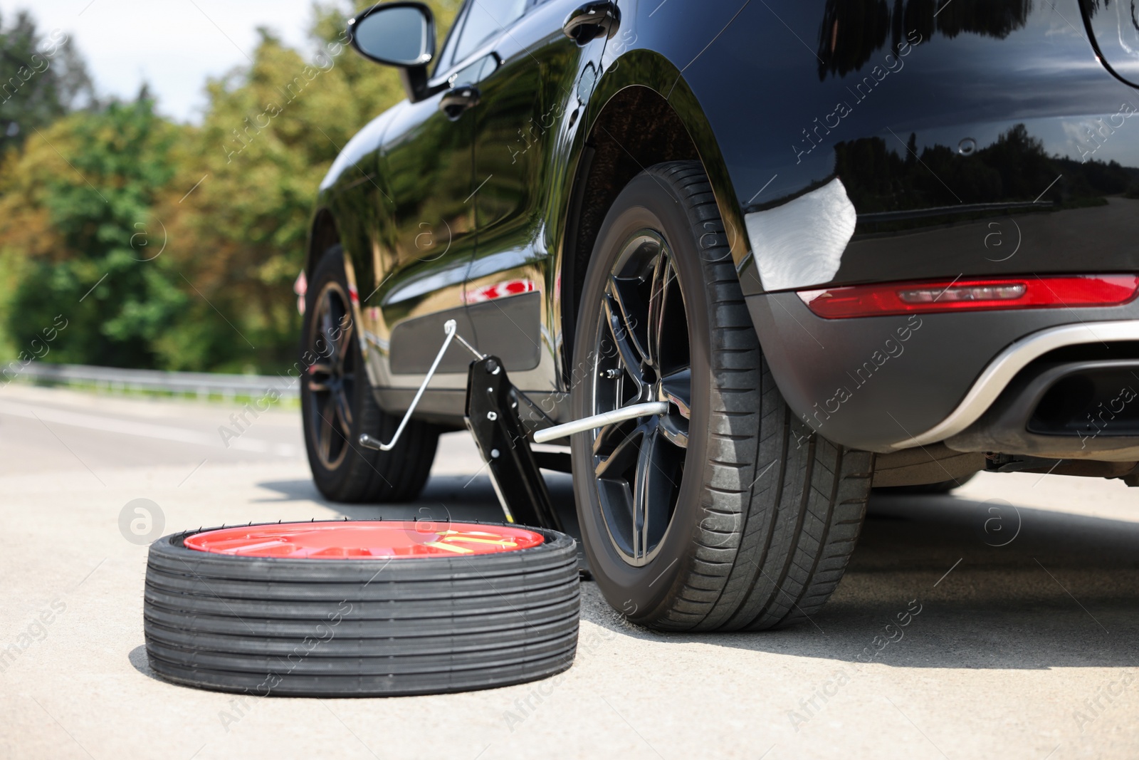 Photo of Tire puncture. New wheel near car on roadside outdoors