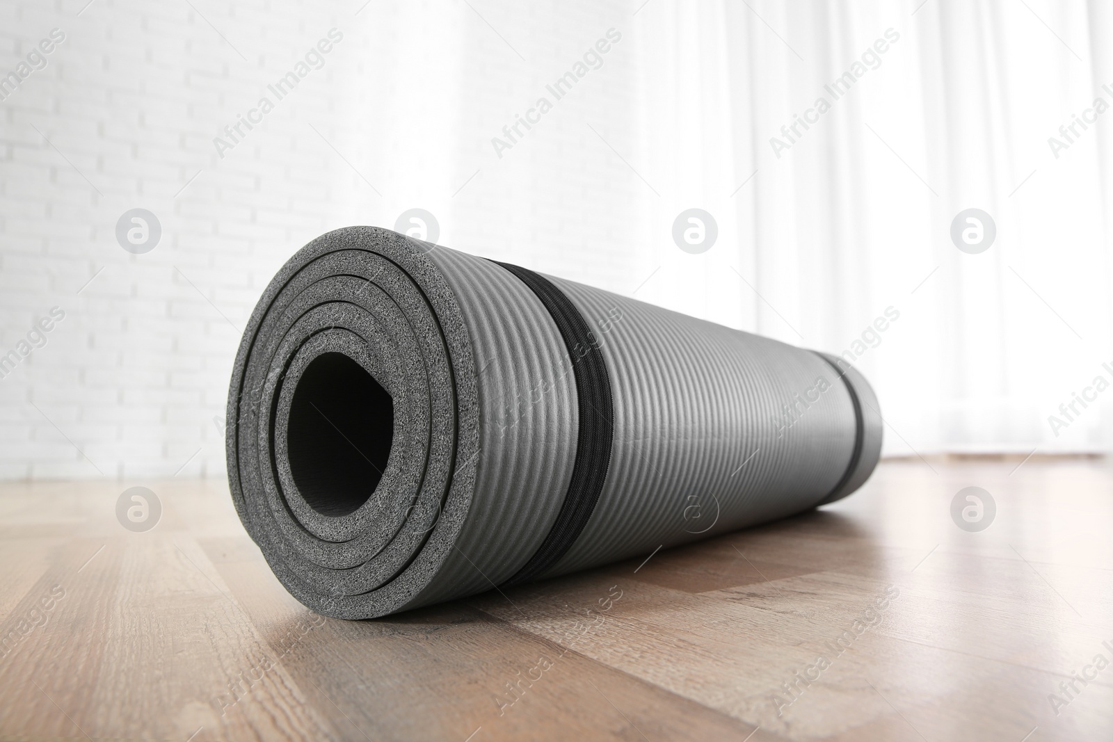 Photo of Rolled grey yoga mat on floor indoors