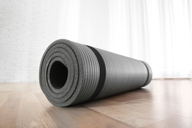 Photo of Rolled grey yoga mat on floor indoors