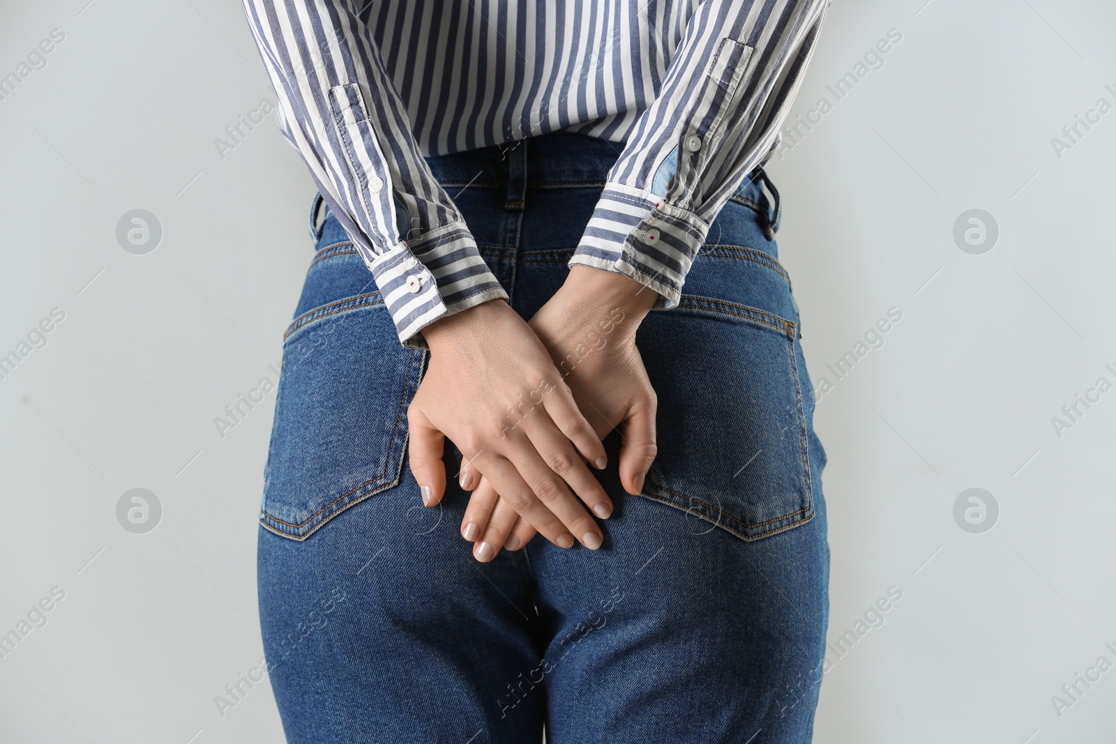 Photo of Woman suffering from hemorrhoid on light grey background, closeup