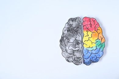 Photo of Logic and creativity. Paper brain with one colorful hemisphere and another grey on white background, top view. Space for text