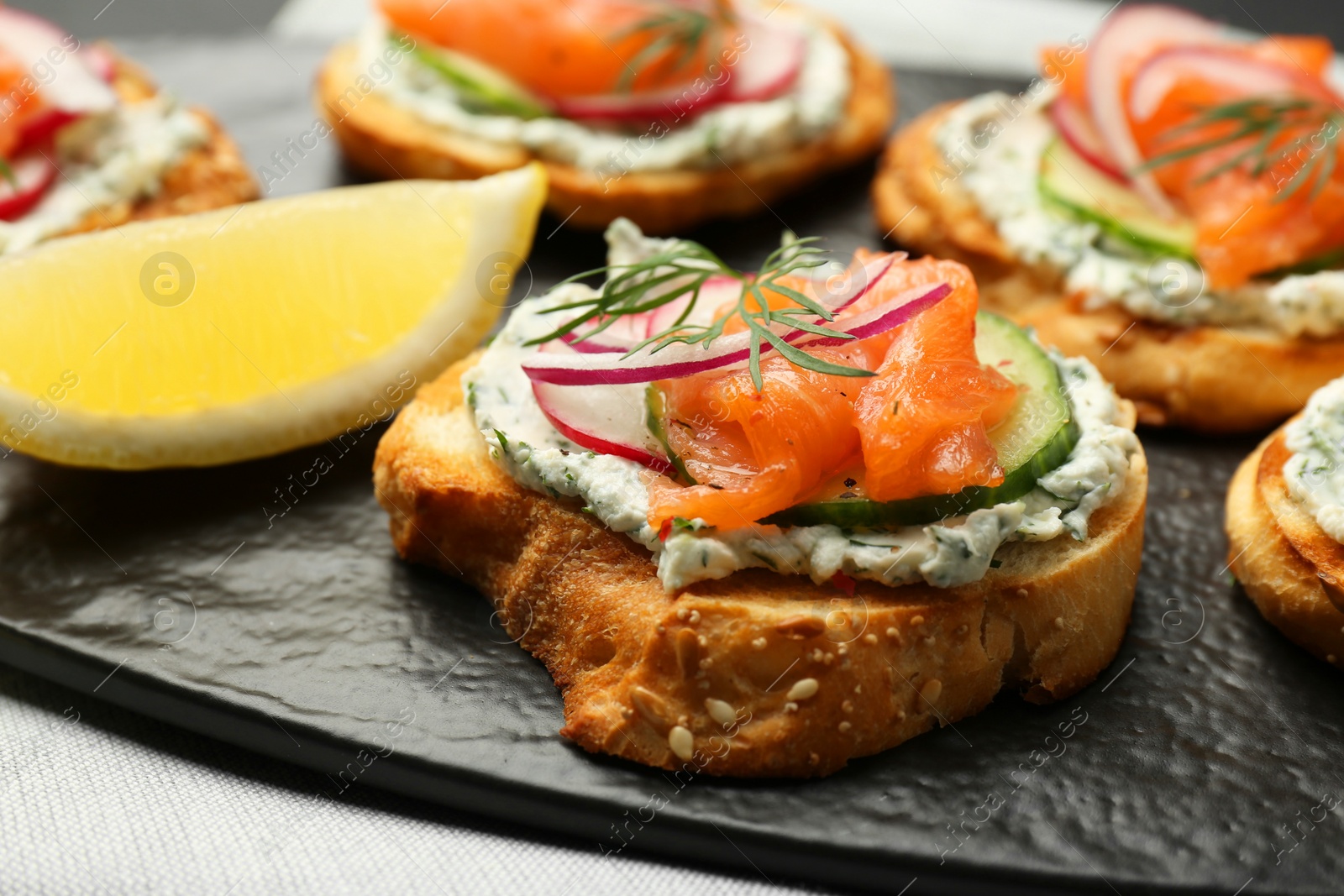 Photo of Tasty canapes with salmon, cucumber, radish and cream cheese on table, closeup