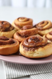 Many tasty cinnamon rolls on white table, closeup