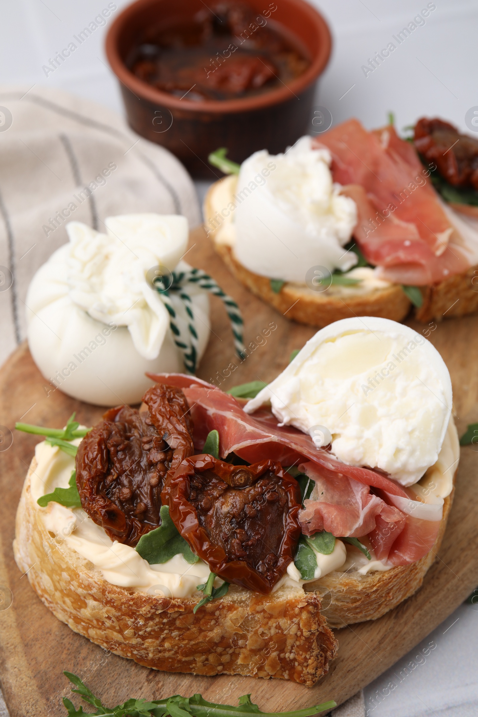 Photo of Delicious sandwiches with burrata cheese, ham and sun-dried tomatoes served on table, closeup