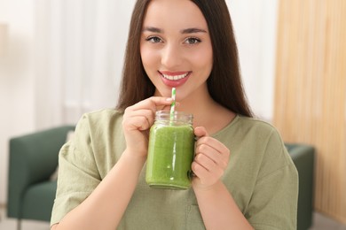 Photo of Beautiful young woman drinking delicious smoothie indoors