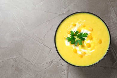 Delicious creamy corn soup served on grey table, top view. Space for text