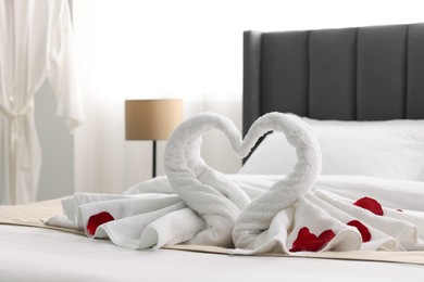 Honeymoon. Swans made of towels and rose petals on bed in room