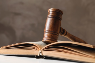 Photo of Wooden gavel and book on table against color background, closeup. Law concept