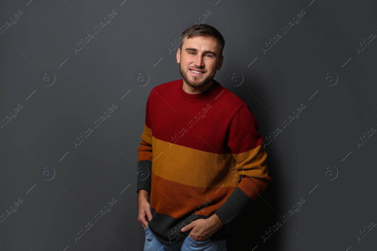 Photo of Handsome young man in warm sweater on dark background