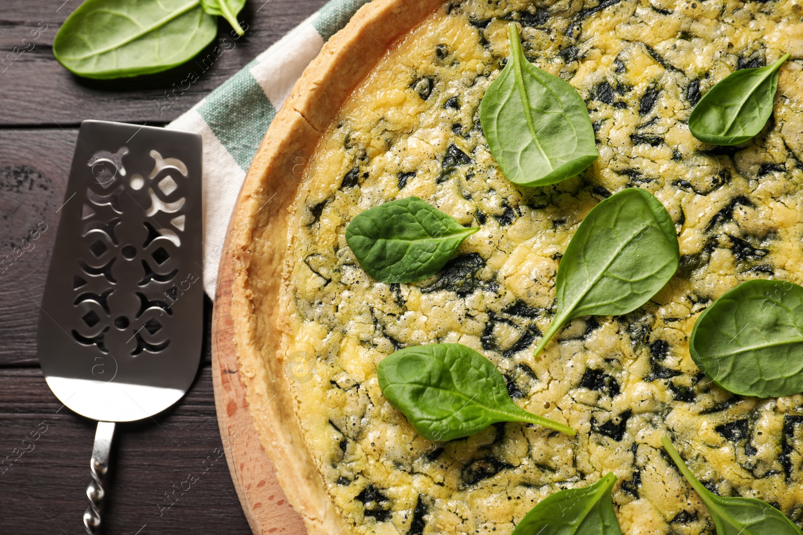 Photo of Delicious homemade spinach pie and spatula on wooden table, flat lay