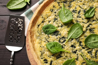 Delicious homemade spinach pie and spatula on wooden table, flat lay