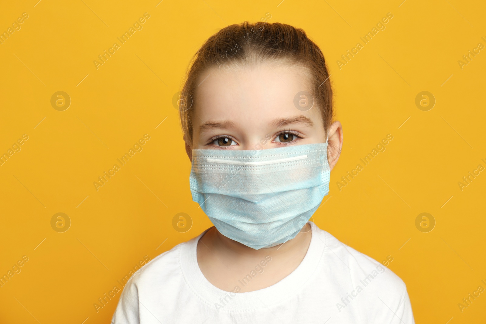 Photo of Cute little girl in protective mask on yellow background