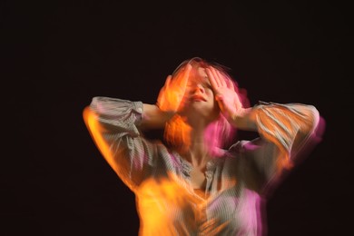 Young woman performing contemporary dance on black background, motion blur effect