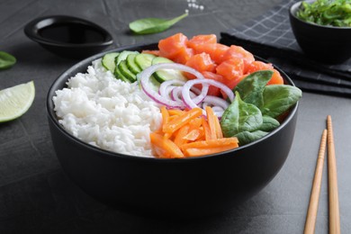 Photo of Delicious poke bowl with salmon and vegetables served on grey table, closeup