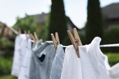 Photo of Washing line with clean clothes in garden, closeup. Drying laundry outside