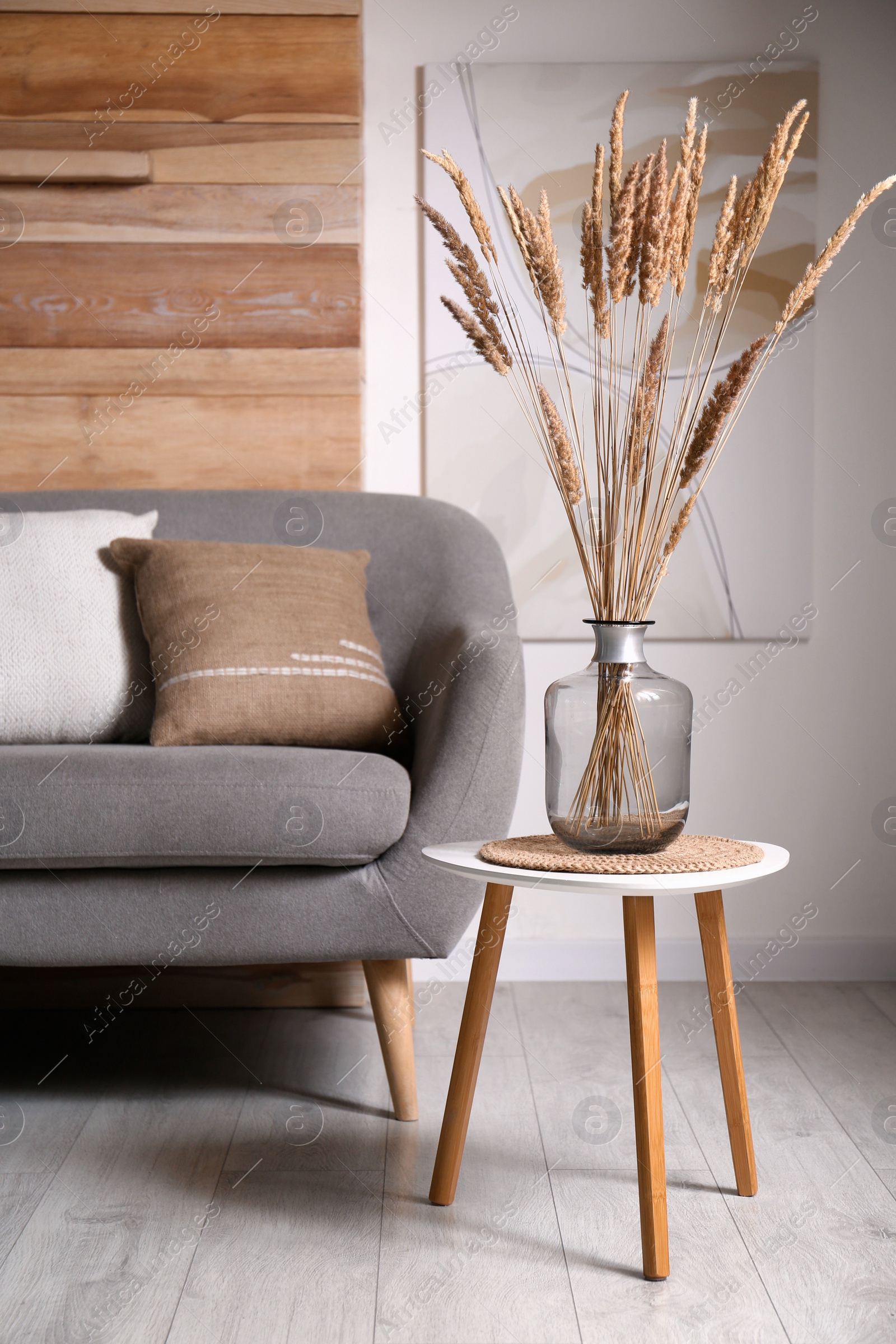 Photo of Vase with decorative dried plants on table in living room. Interior design