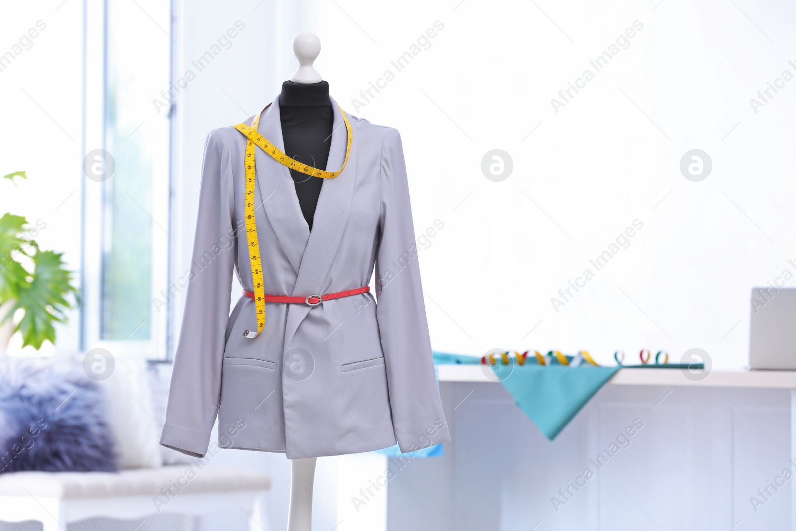 Photo of Mannequin with jacket and measuring tape in tailor studio