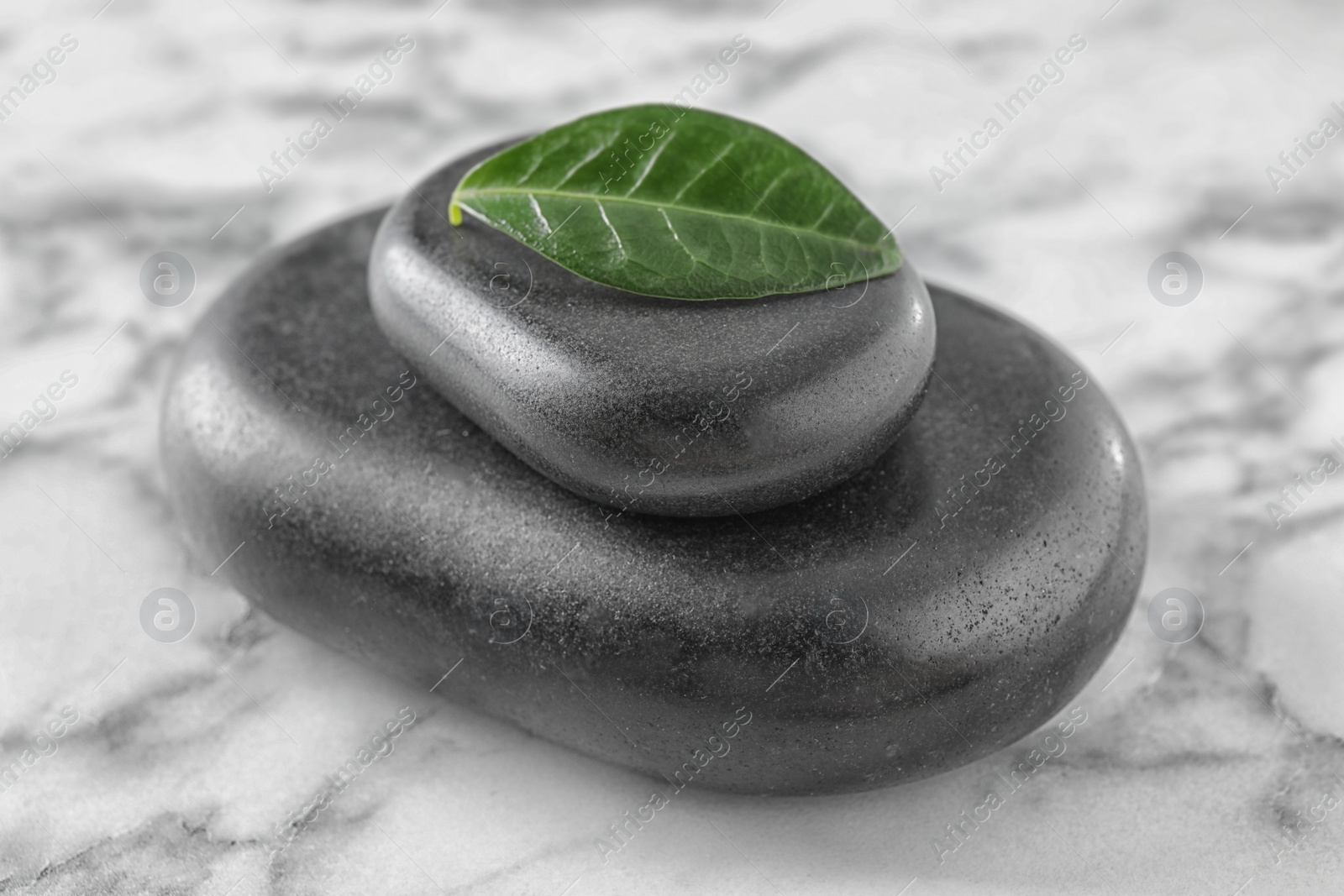 Photo of Spa stones and green leaf on marble table