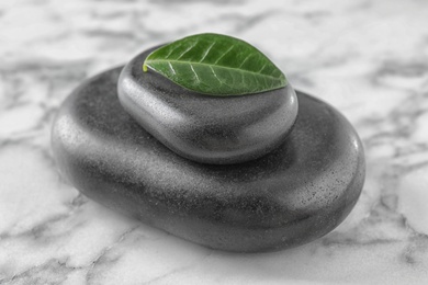 Spa stones and green leaf on marble table