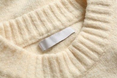 Blank clothing label on white cashmere sweater, top view