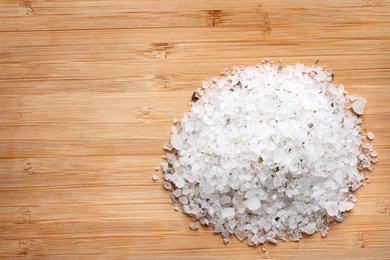 Photo of Pile of white sea salt on wooden table, top view with space for text. Spa treatment