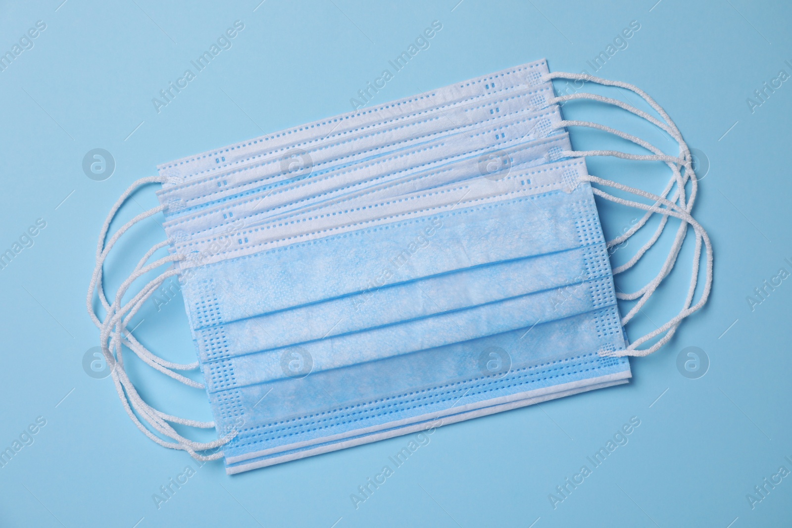 Photo of Protective masks on light blue background, flat lay. Safety equipment