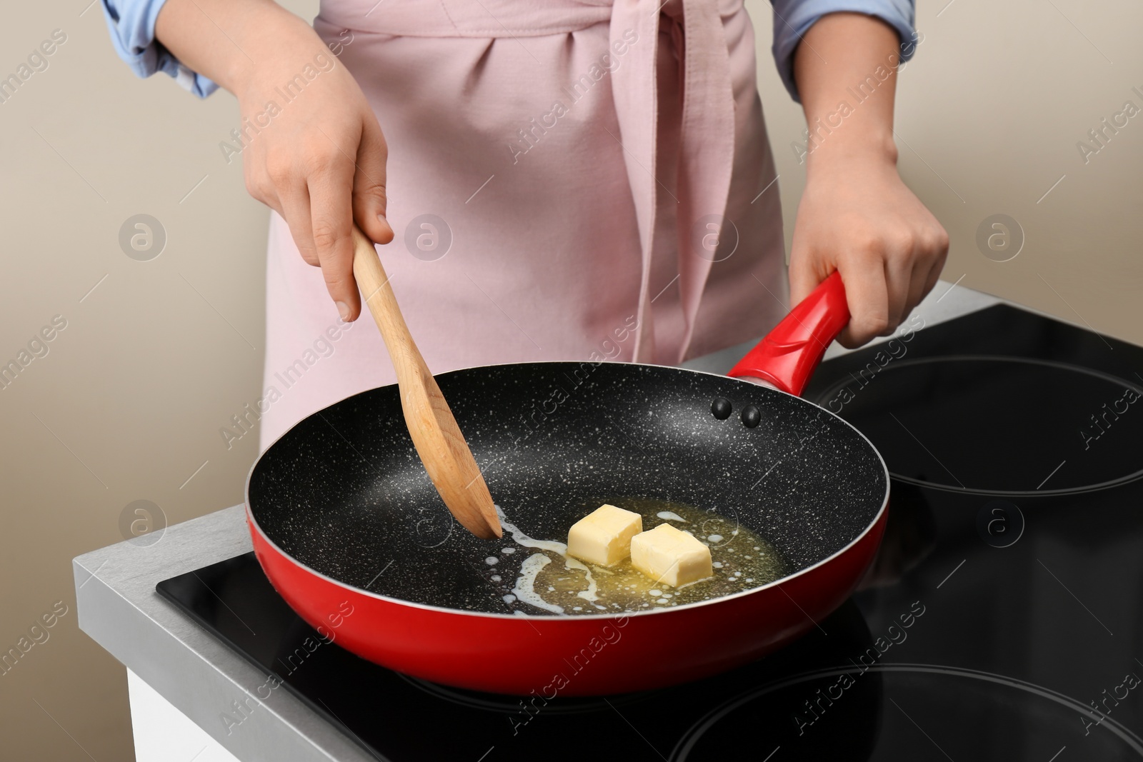 Photo of Woman stirring butter in frying pan on electric stove, closeup