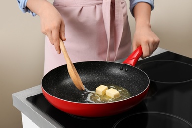 Photo of Woman stirring butter in frying pan on electric stove, closeup