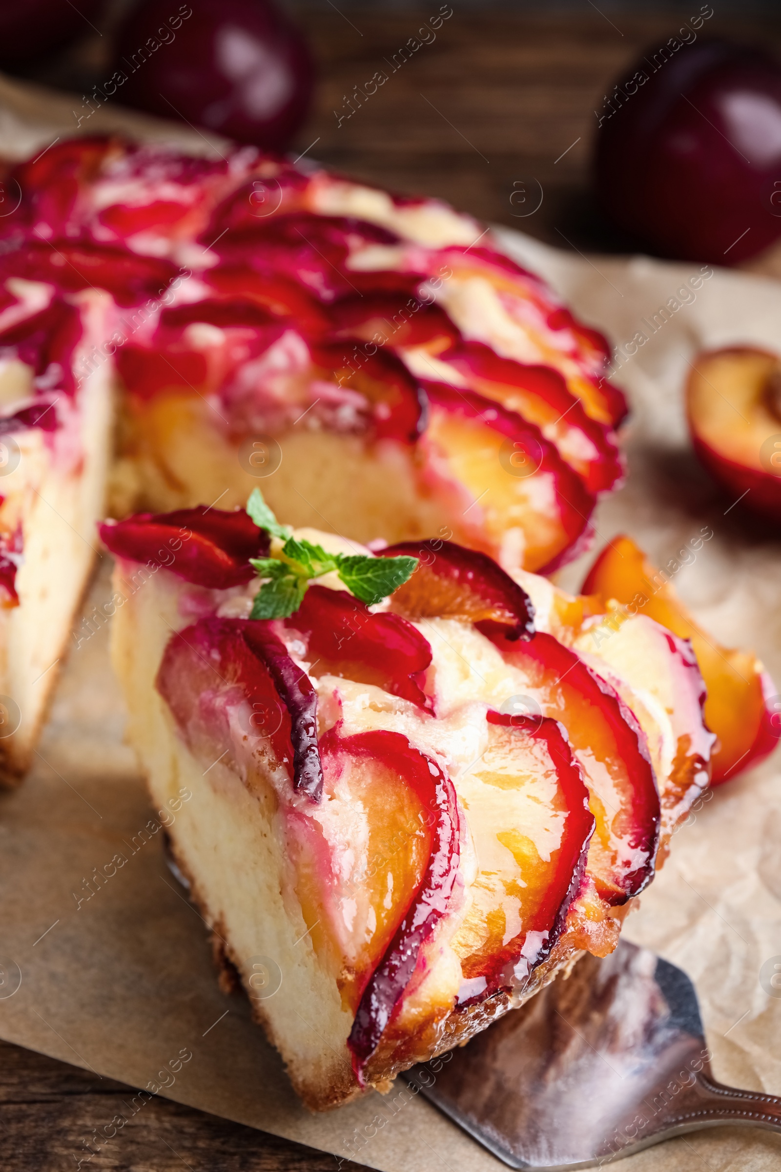 Photo of Delicious cake with plums on wooden table, closeup