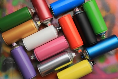 Photo of Cans of different graffiti spray paints on color background, flat lay