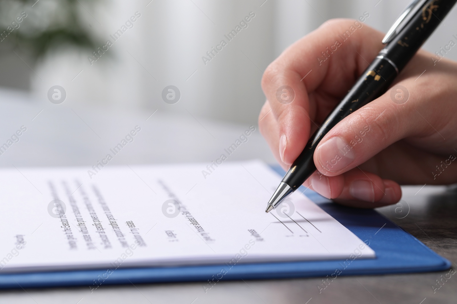 Photo of Woman signing document at dark table indoors, closeup. Space for text