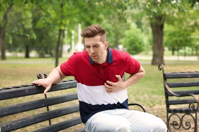 Photo of Young man having chest pain in park. Heart attack