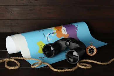 Photo of Modern binoculars, rope, compass and map on wooden table