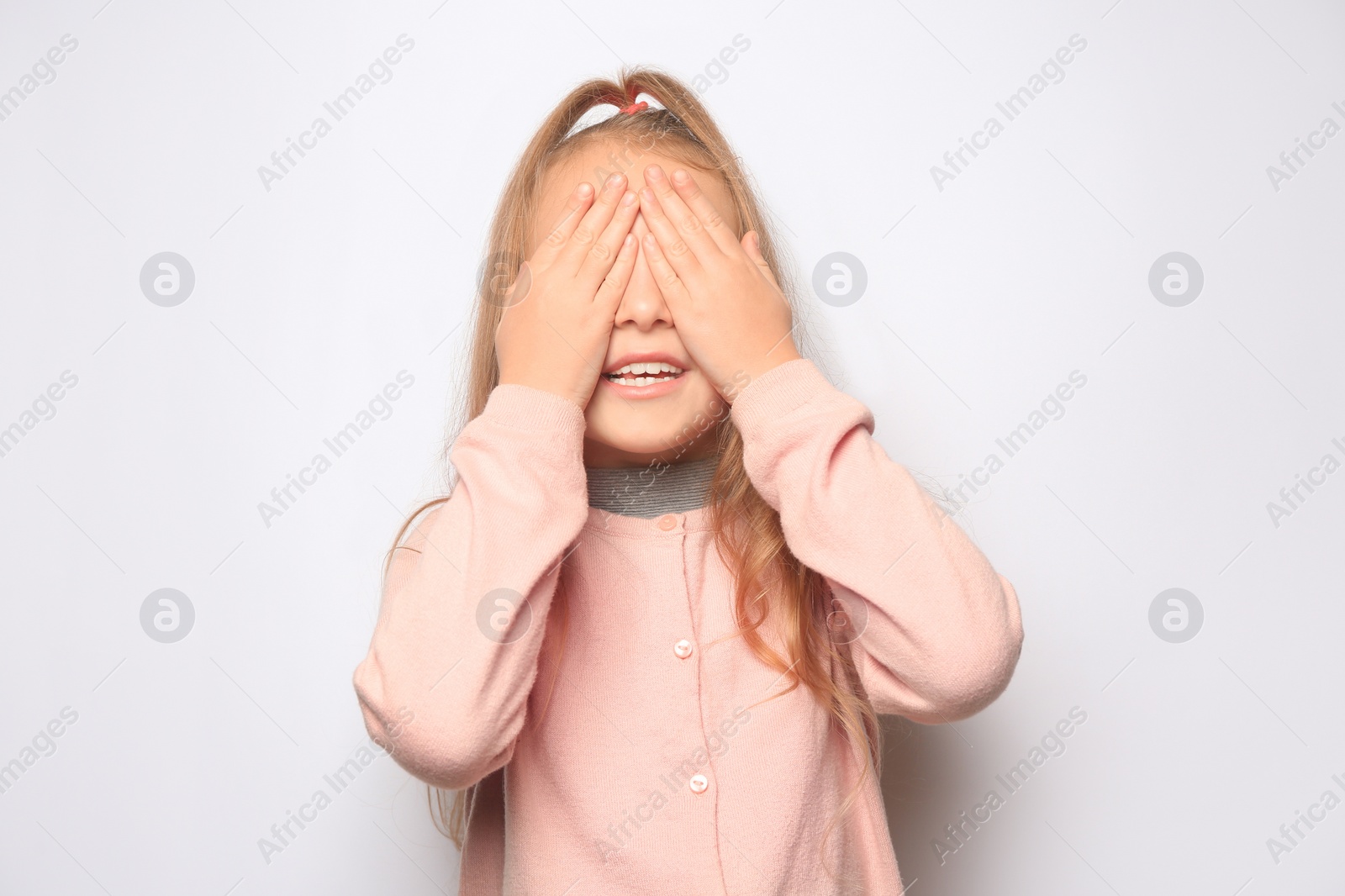 Photo of Happy little girl closing her eyes with hands on white background