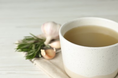 Photo of Mug with delicious bone broth on white wooden table, closeup. Space for text