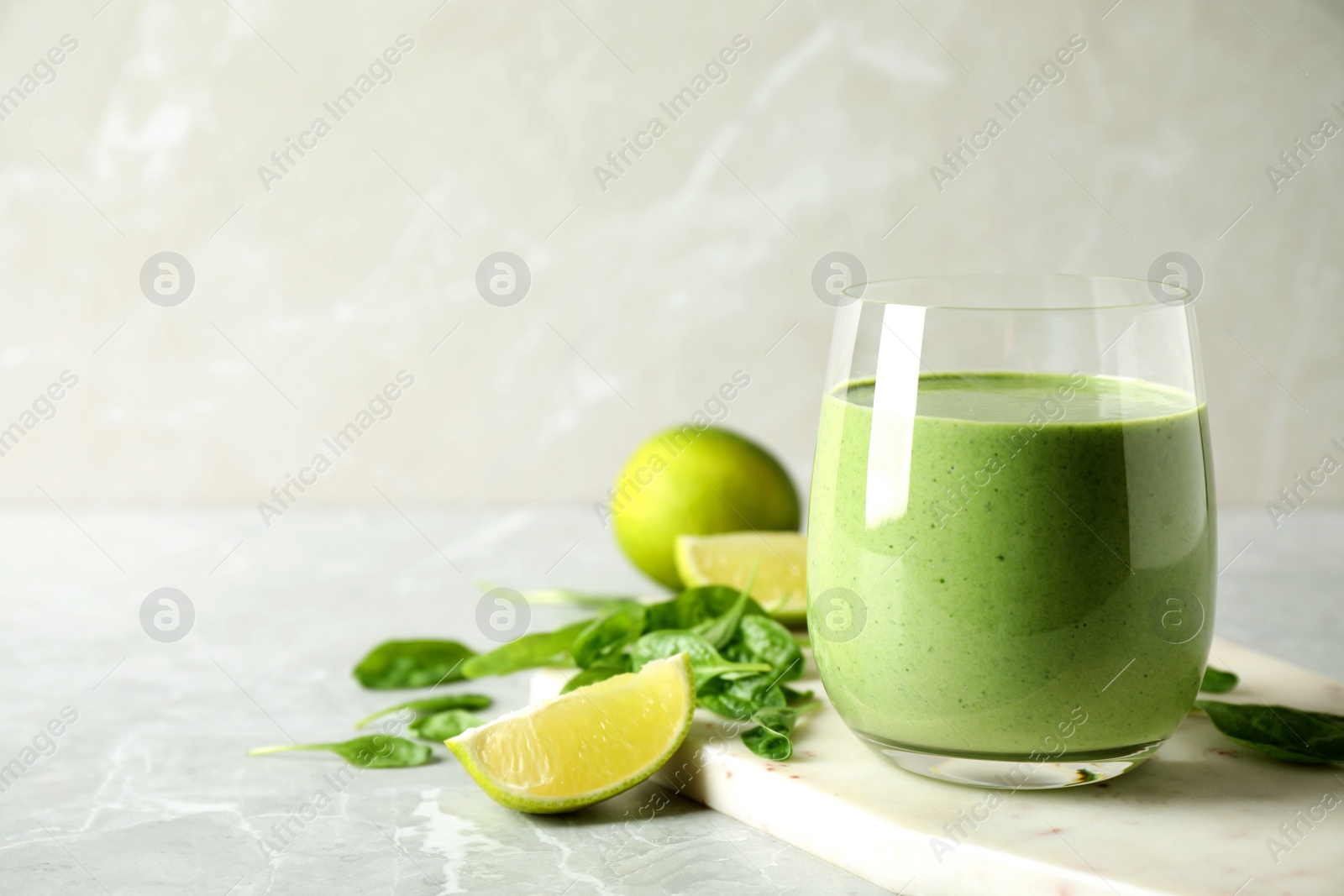 Photo of Glass of healthy green smoothie with fresh spinach on light table. Space for text