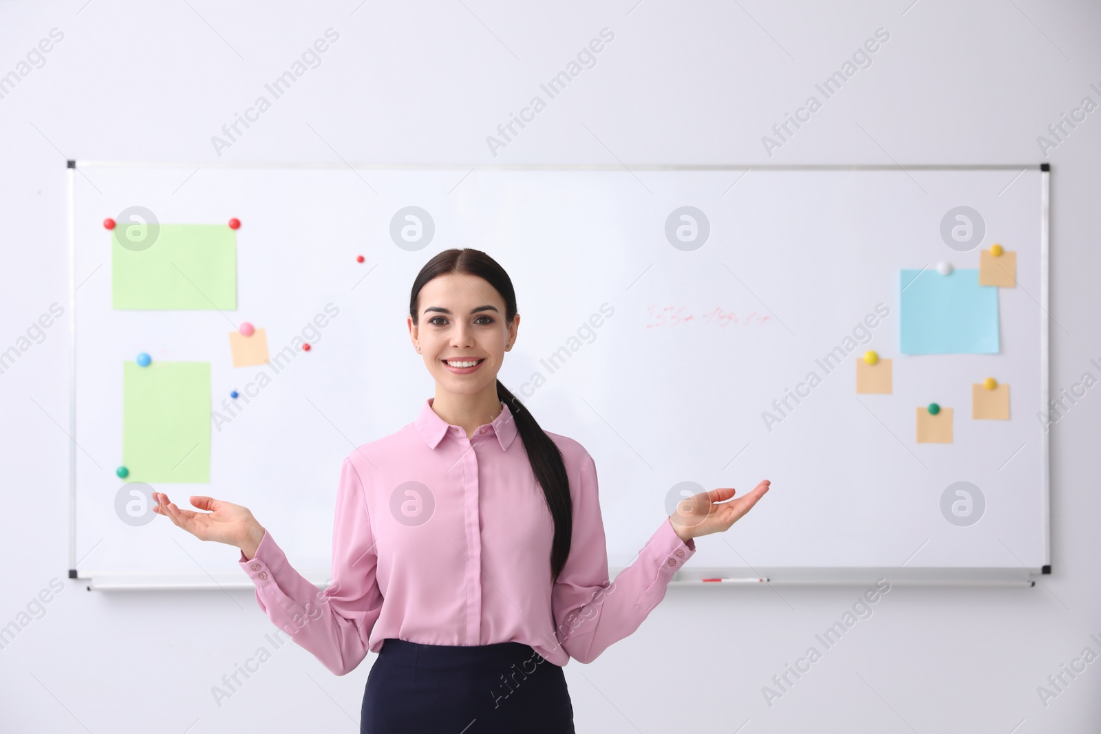 Photo of Young teacher near whiteboard in modern classroom