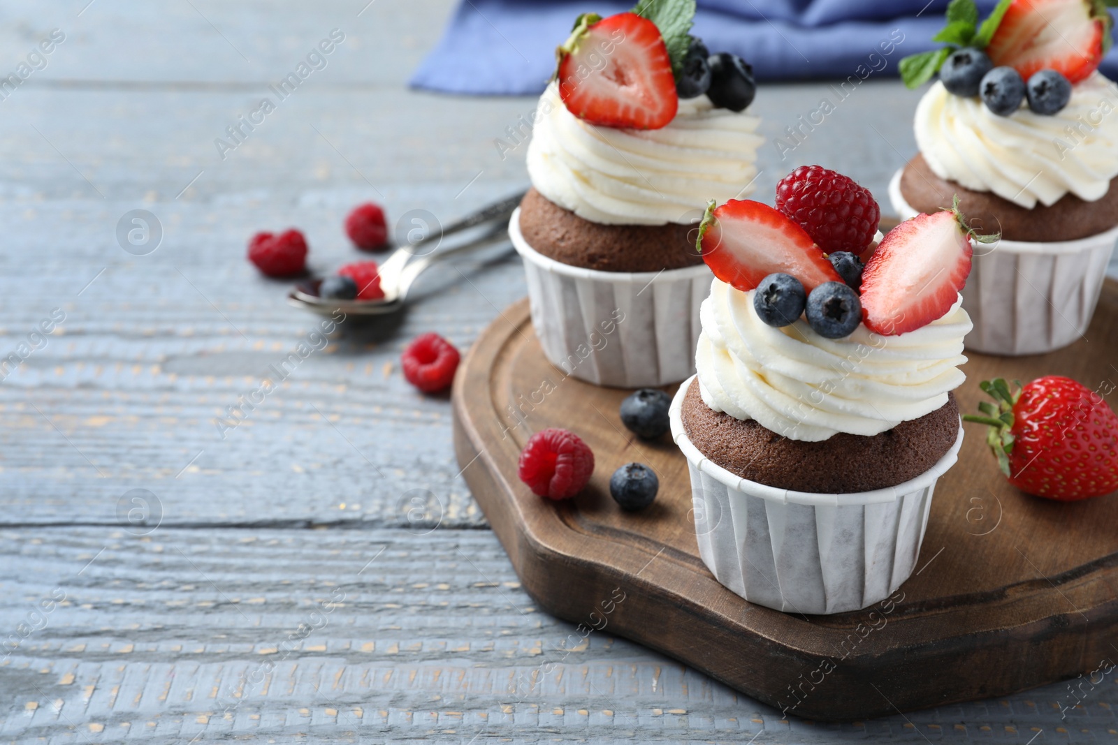 Photo of Sweet cupcakes with fresh berries on wooden table. Space for text