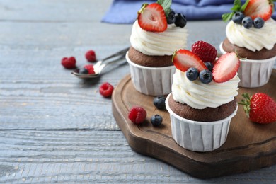 Photo of Sweet cupcakes with fresh berries on wooden table. Space for text