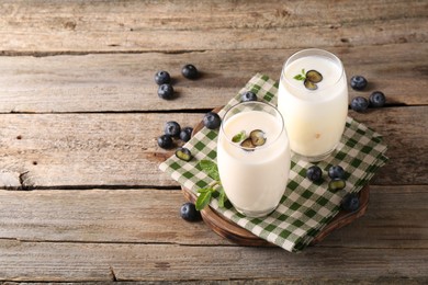 Photo of Composition with tasty yogurt in glasses and blueberries on wooden table. Space for text
