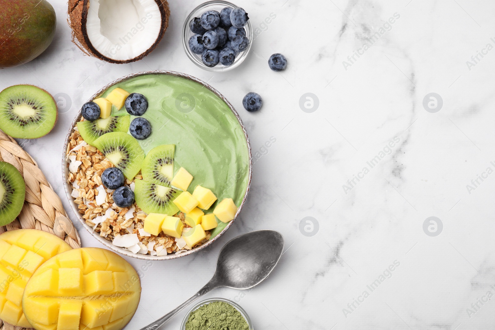 Photo of Tasty matcha smoothie bowl with fresh fruits and oatmeal served on white marble table, flat lay with space for text. Healthy breakfast